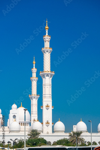 Close-up of the Sheikh Zayed Grand Mosque, showcasing its intricate white marble domes and elegant architectural details against a vivid blue sky. 