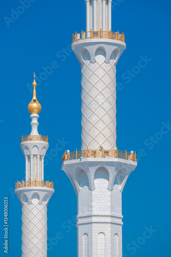 Close-up of the Sheikh Zayed Grand Mosque, showcasing its intricate white marble domes and elegant architectural details against a vivid blue sky. 