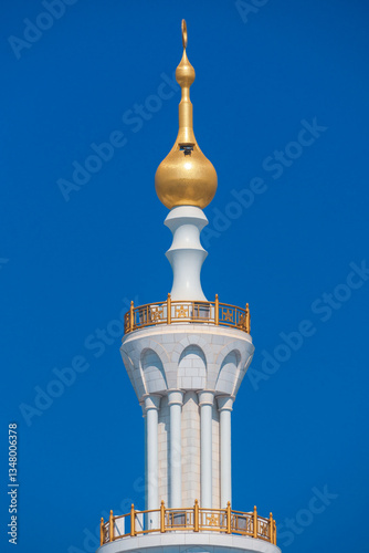 Close-up of the Sheikh Zayed Grand Mosque, showcasing its intricate white marble domes and elegant architectural details against a vivid blue sky. 