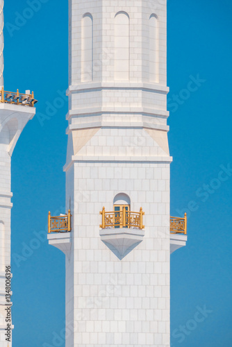 Close-up of the Sheikh Zayed Grand Mosque, showcasing its intricate white marble domes and elegant architectural details against a vivid blue sky. 
