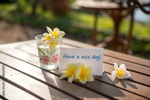Have a nice day card on wooden outdoor table with flowers and warm sunlight
