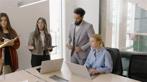 In a modern office, diverse professionals engage in discussions while using laptops, promoting collaboration and boosting productivity for successful project outcomes that benefit all