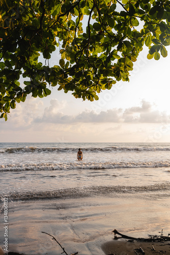 Woman standing in the ocean at tropical beach during sunset