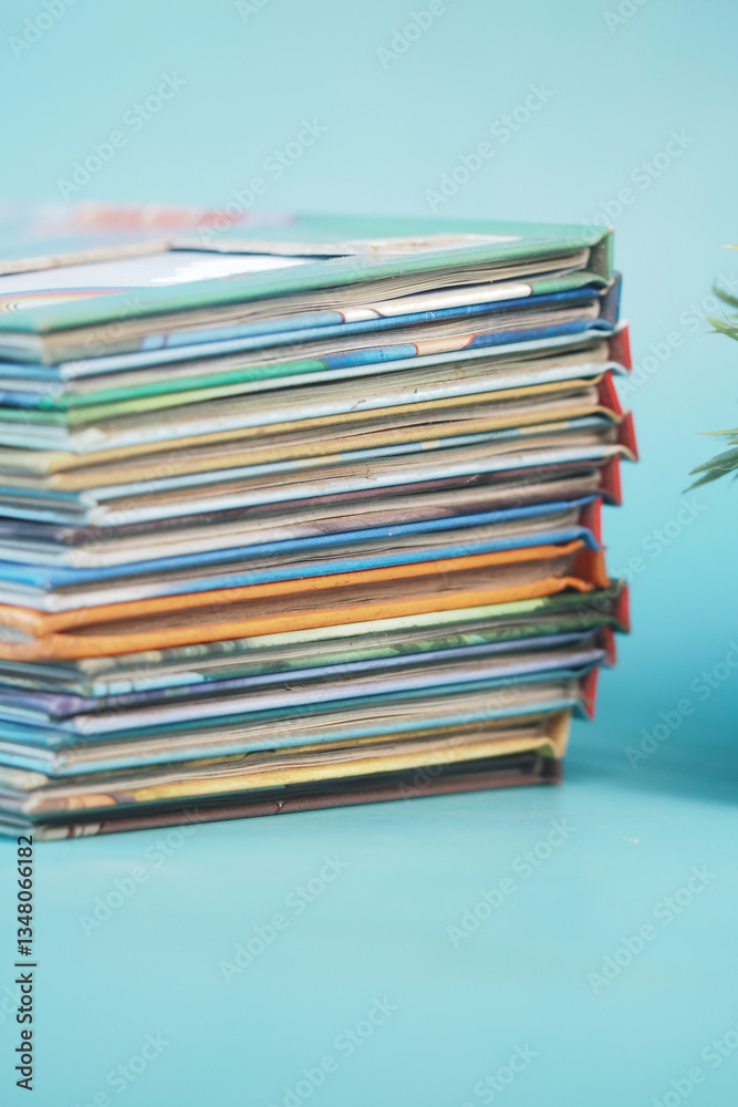 Stack of colorful magazines resting on a light blue surface Stack of colorful magazines resting on a light blue surface