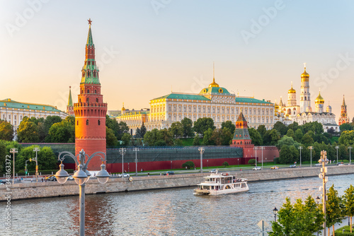 View of Kremlin with Vodovzvodnaya tower, Grand Kremlin Palace from repaired Bolshoy Kamenny Bridge in Moscow city on sunny summer day. Cruise ship sails on the Moscow river