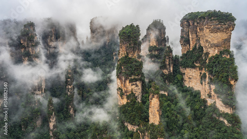 Incredible mountain landscape. The high cliffs  pillars are shrouded in fog. Peaks in the clouds. Green vegetation on the slopes and in the valley. China. Zhangjiajie National Forest Park. Avatar