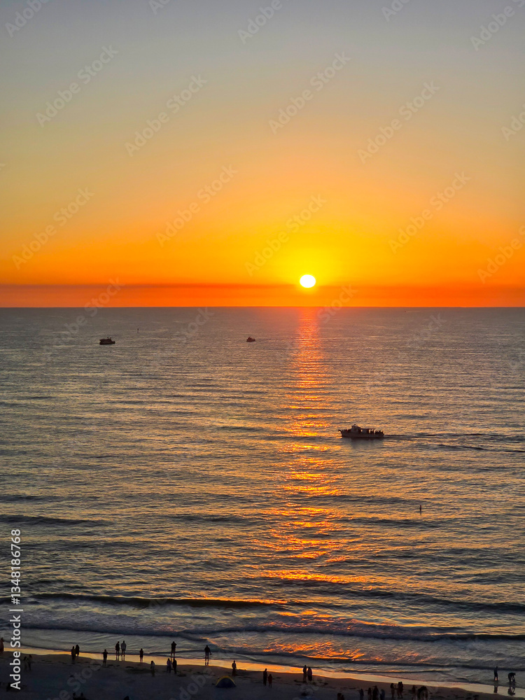 Obraz premium A stunning sunset over the Gulf of Mexico at Clearwater Beach with vast ocean water and boats sailing in Clearwater Florida USA