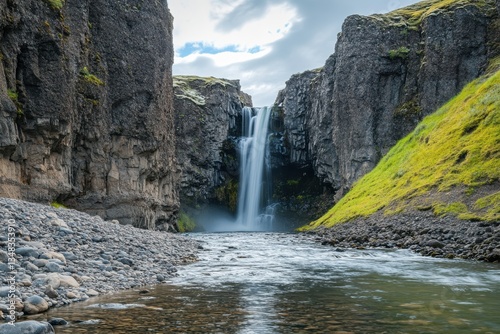 Majestic waterfall cascading through rugged cliffs in a serene Icelandic landscape at midday
