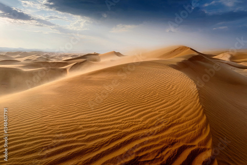 Desert, dunes of yellow sand. A sandstorm lifts sand into the dark sky.
