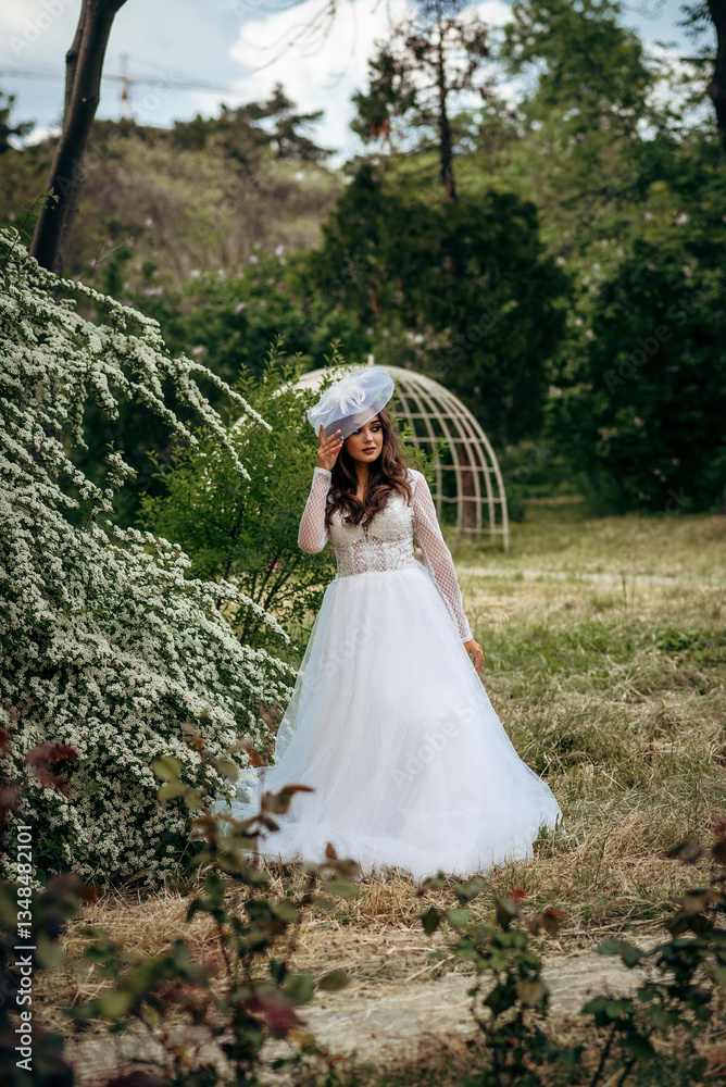 Fototapeta premium Elegant Bride in a Flowing White Gown Surrounded by Lush Greenery 