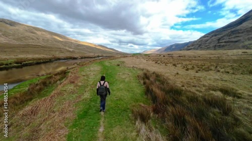 Woman backpacker hiking on trail by the Erriff river near Aesleagh falls, county Mayo, Ireland, aerial, Irish landscape, nature and mountains, hyper lapse photo