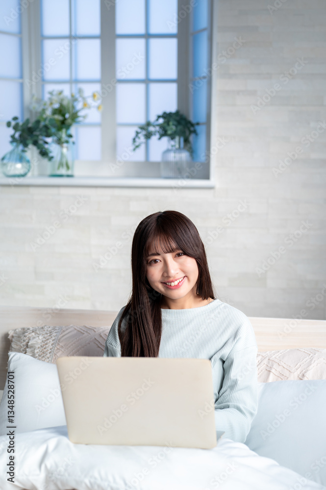 ベッドでパソコンを持つ日本人女性 ベッドでパソコンを持つ日本人女性