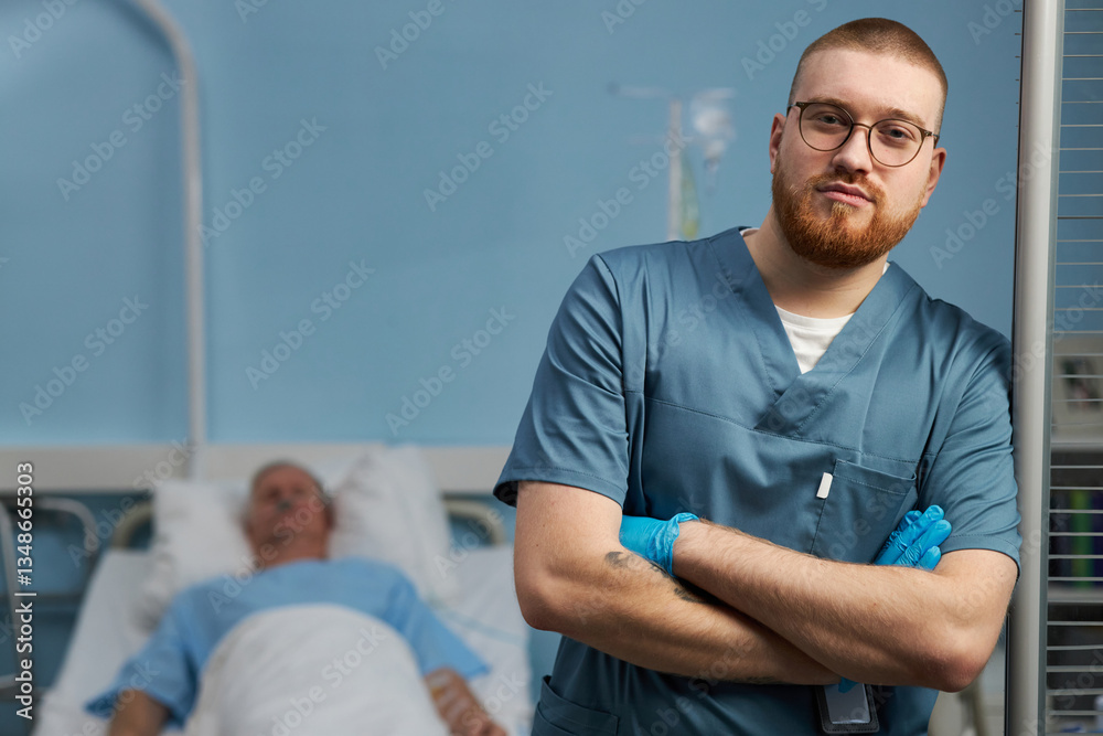 Obraz premium Doctor standing with arms crossed in hospital room by patient bedside wearing medical scrubs. Patient resting on hospital bed covered with a blanket in the background
