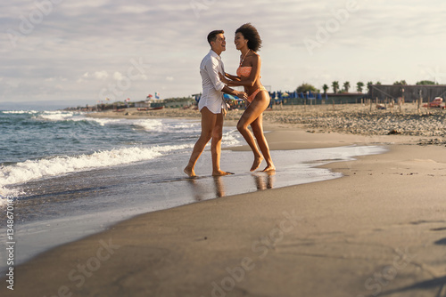 Happy couple playing on the beach at sunset during summer vacation