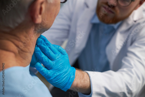 Senior being examined by healthcare professional wearing blue gloves during a routine check-up in clinical environment