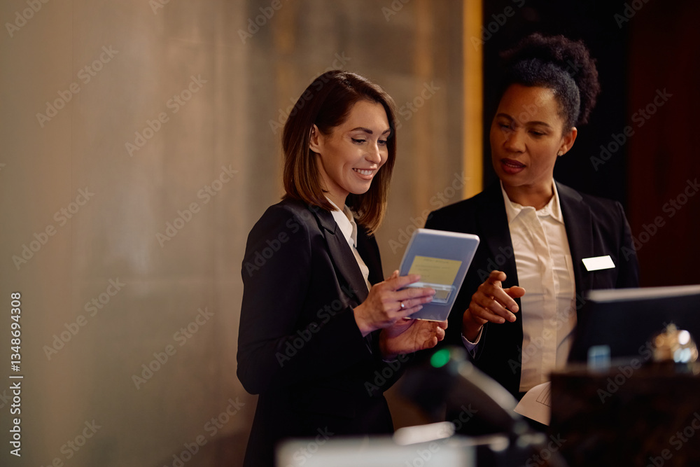 Female hotel receptionists using digital tablet while working at front desk. Female hotel receptionists using digital tablet while working at front desk.