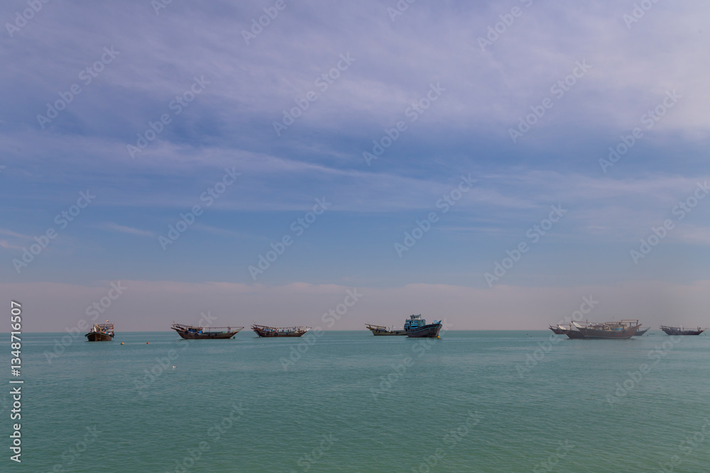 Fishing vessels rest in the calm waters of Bushehr, embraced by the endless sky and serene sea. Fishing vessels rest in the calm waters of Bushehr, embraced by the endless sky and serene sea.