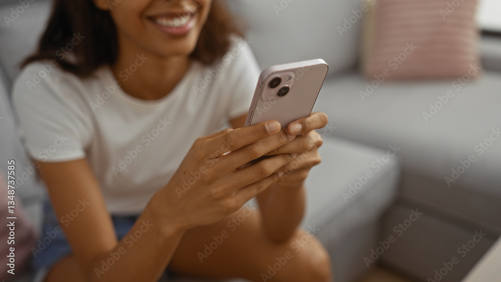Young woman smiling while using smartphone indoors at home in a comfortable living room setting. Young woman smiling while using smartphone indoors at home in a comfortable living room setting.