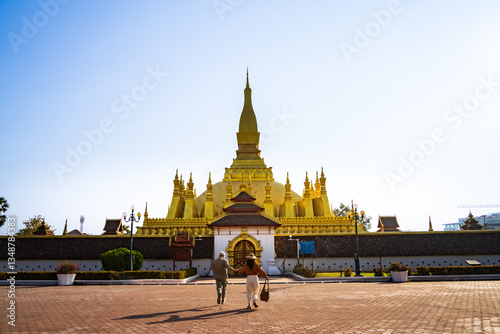 A couple walking towards the iconic Pha That Luang temple in Laos, capturing the beauty and cultural significance of this landmark
