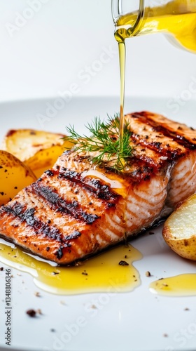 Grilled salmon with dill and fried potatoes drizzled with olive oil on a white plate