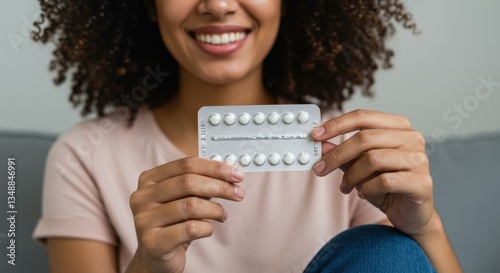 Happy woman holding a blister pack of pills, showcasing a positive and relaxed attitude while managing her health.
