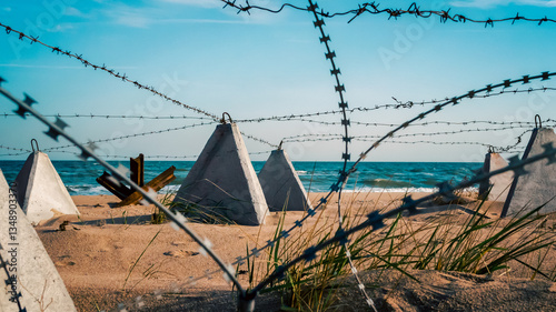 barbed wire and concrete military fence on the beach near the sea in Crimea