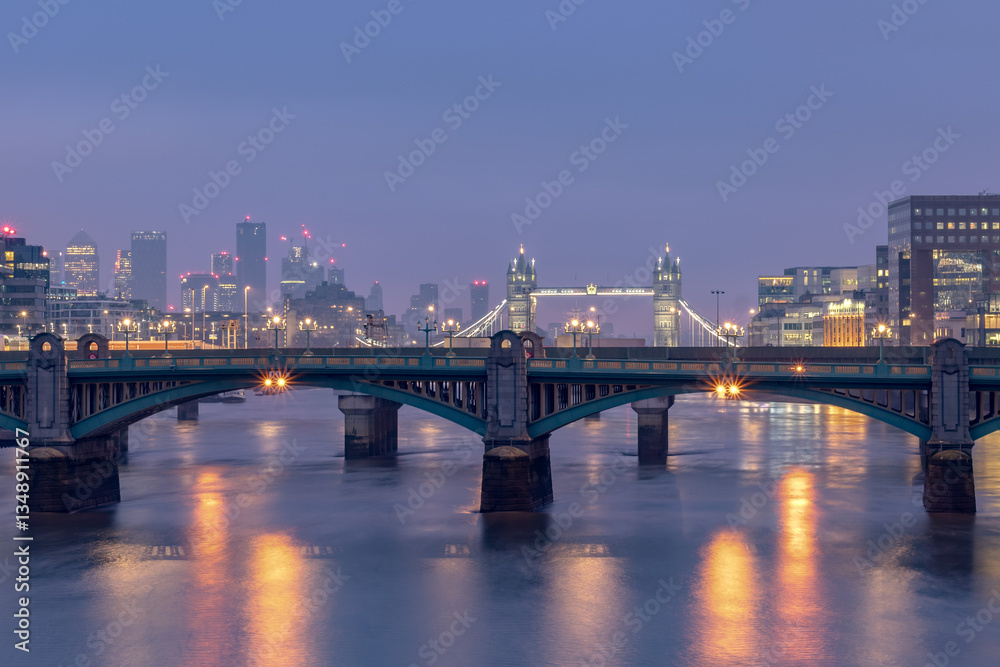 Illuminated buildings of the London United Kingdom city skyline along the Thames River. Photo contains the iconic London Tower Bridge. Illuminated buildings of the London United Kingdom city skyline along the Thames River. Photo contains the iconic London Tower Bridge.