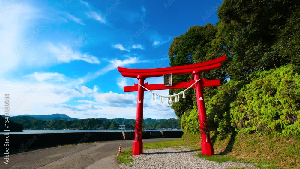 Red gate (Torii) at Otonashi Shrine by the sea, with a forest next to the gate under blue skies Red gate (Torii) at Otonashi Shrine by the sea, with a forest next to the gate under blue skies