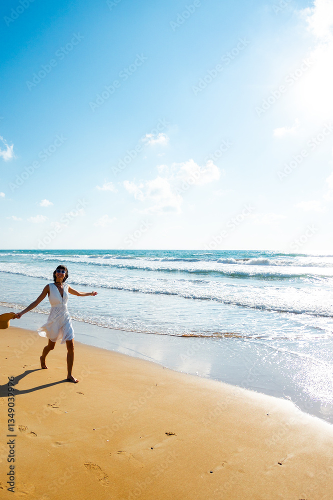 Happy beautiful young woman walking on the beach.Carefree girl walking along the beach on a sunny day. Happy beautiful young woman walking on the beach.Carefree girl walking along the beach on a sunny day.