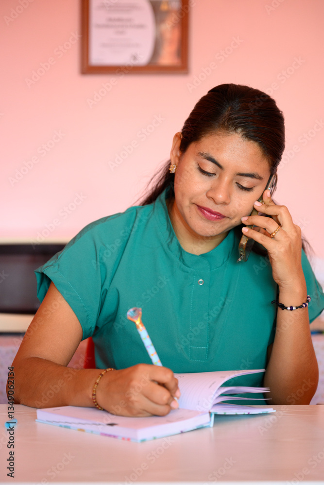 Latin nurse taking notes while speaking on the phone Latin nurse taking notes while speaking on the phone