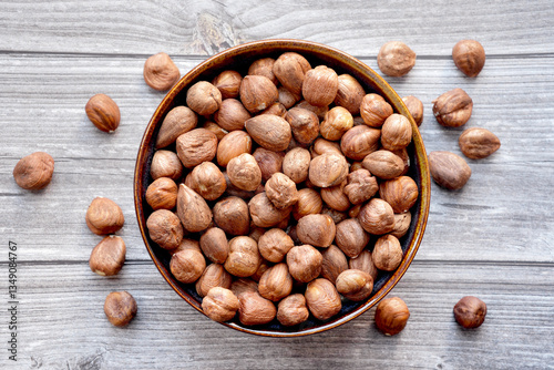 Photograph of dried hazelnuts without shell in a bowl on wooden background. Top view.  Healthy eating and snack, whole foods. Source of natural fats, minerals and vitamins. 