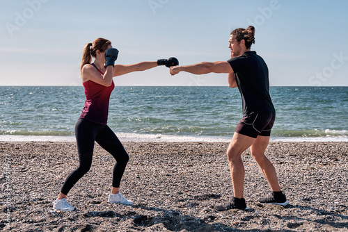 Couple training boxing on the beach, practicing punches at seashore