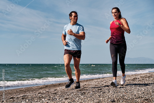Couple running on the beach, promoting healthy lifestyle and fitness together