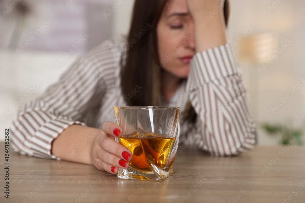 Alcohol addiction. Woman with glass of whiskey at wooden table indoors, selective focus Alcohol addiction. Woman with glass of whiskey at wooden table indoors, selective focus