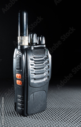 Black walkie talkie on a table mat with a dark background behind