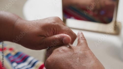Senior woman in 60s nourishing hand cream to skin, taking care of hands.
