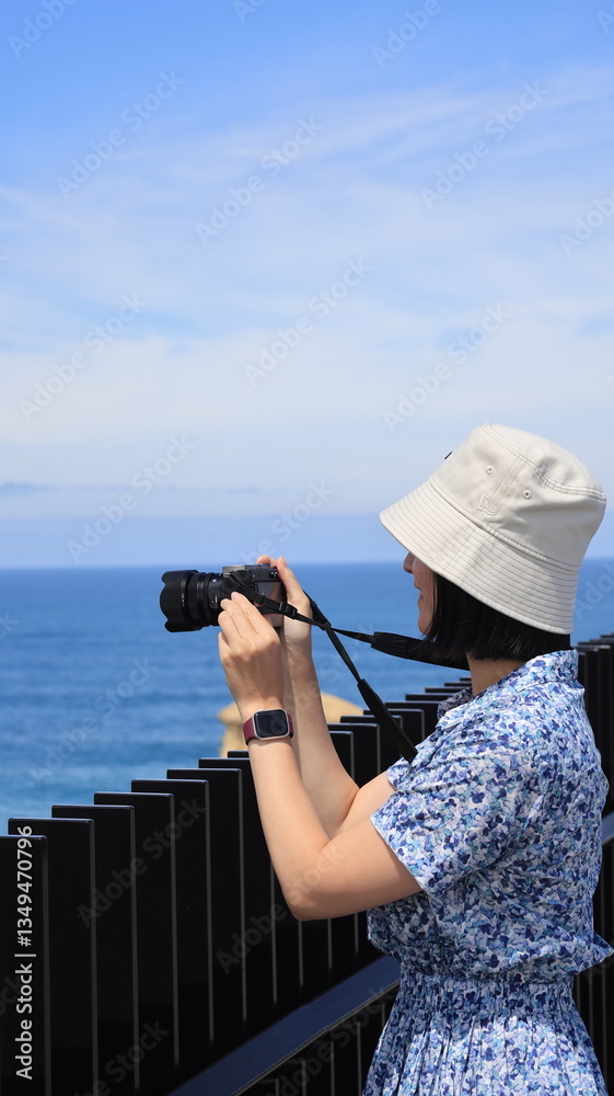 Obraz premium woman in a blue dress taking a photo of the sea