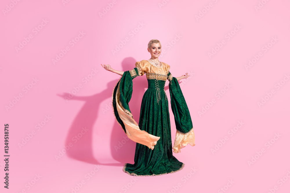 Fototapeta premium Glamorous woman in medieval royal dress posing gracefully against pink background