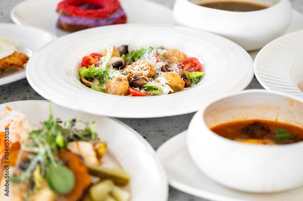 A variety of dishes on a white table include fresh salad with croutons, cherry tomatoes, mushrooms, soup, fried egg, and dessert. Vibrant colors and diverse food options. A variety of dishes on a white table include fresh salad with croutons, cherry tomatoes, mushrooms, soup, fried egg, and dessert. Vibrant colors and diverse food options.