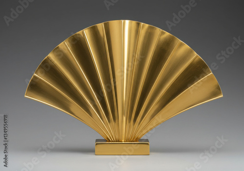 A golden fan shaped sculpture with radiating lines on a rectangular base against a gray background photo