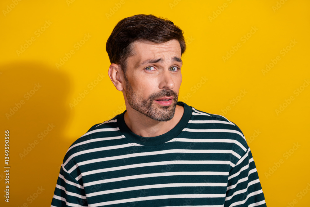 Portrait of a bearded man in a striped shirt and gesture, against a vibrant yellow background, evoking casual style and charm.