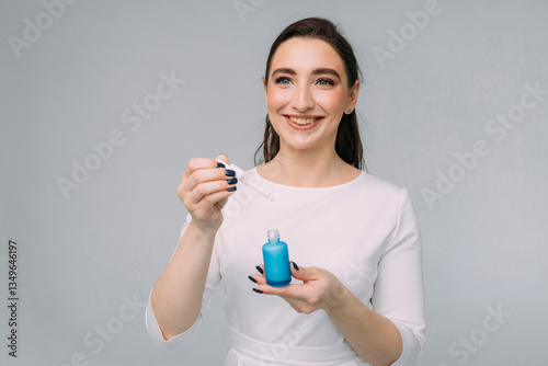 girl with long dark hair holds a bottle of cosmetic serum in her hands. Serum with retinol, niacinamide, vitamin C, anti-wrinkle