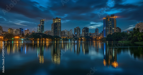 Sunset over Bangalore skyline reflected in serene waterfront.