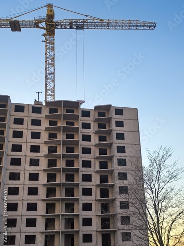 A tall building is under construction with a crane in front