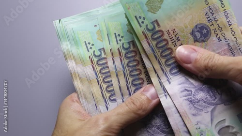 Close up view of woman's hands counting a big stack of Vietnamese currency notes (VND). Cash money of five hundred thousand dong denomination. Real time motion video.