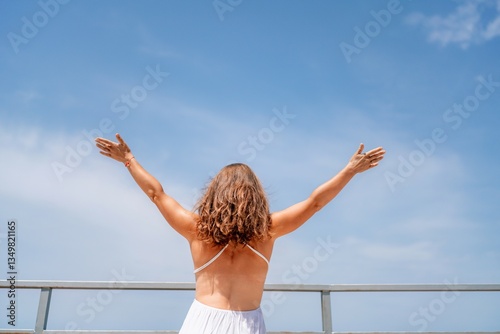 Woman Freedom Sky: Back view, woman raising arms outdoors, joyful moment, feeling liberated on balcony.