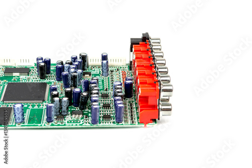 A close-up of the processor microchip surrounded by other electrical components on a green circuit board. Also on the board is a row of several speaker connectors.