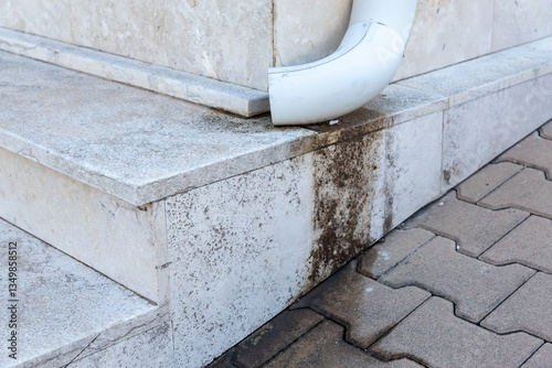  Downspout drainage issue on stone steps highlighting potential maintenance and water damage concerns.