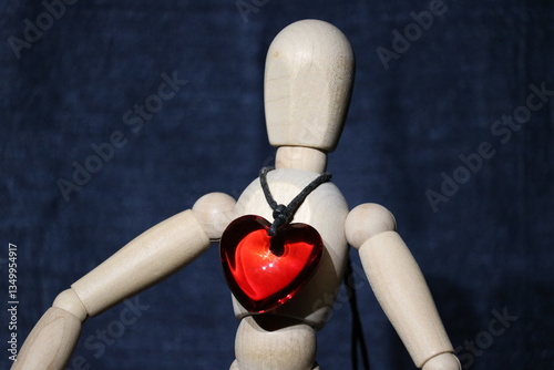 Figure of a wooden toy man with a precious stone in the form of a red heart