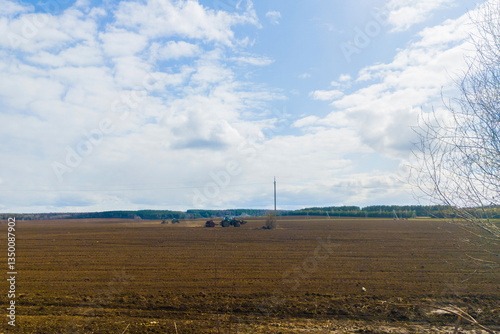 Spring autumn season countryside works.Harvesting farming wheat.Agricultural vehicle machine tractor is working on plowed field on sunny daytime.